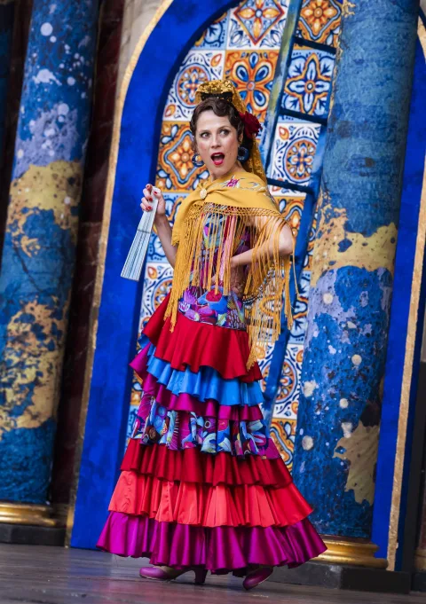 A white Spanish actress with brown hair, dressed in a colourful flamenco outfit.