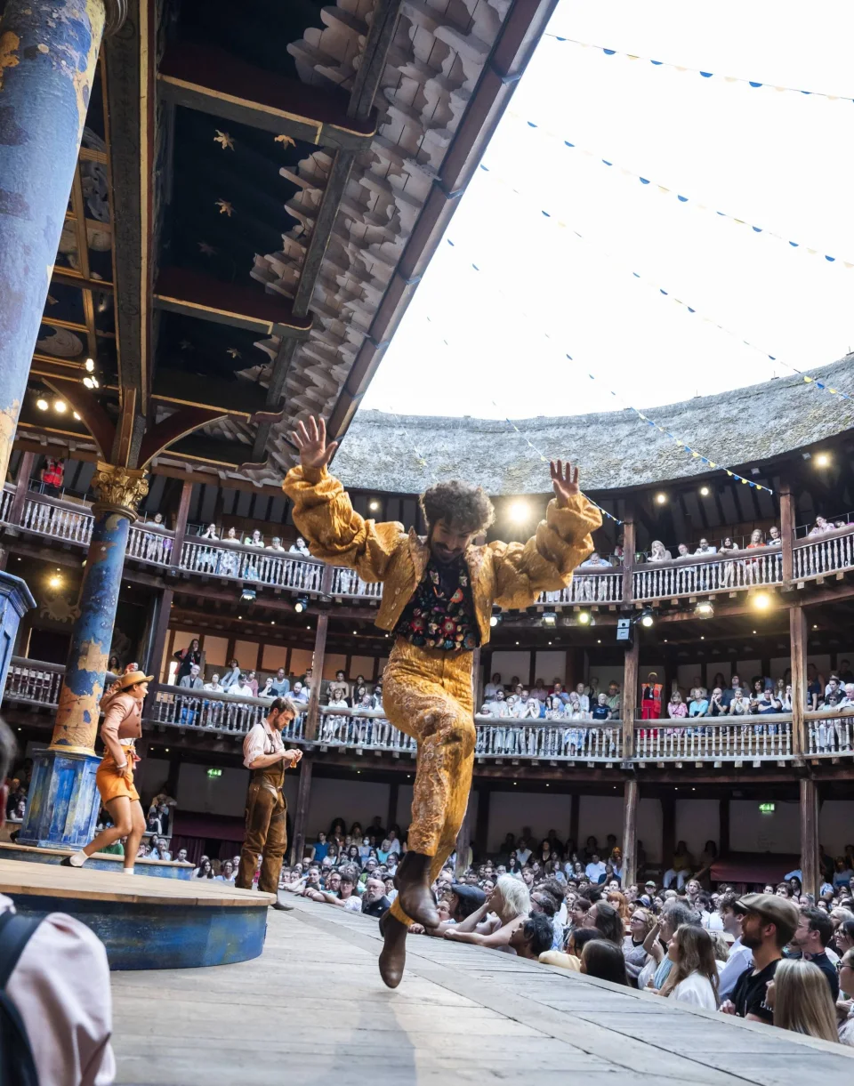 An actor in a gold suit leaps into the air.