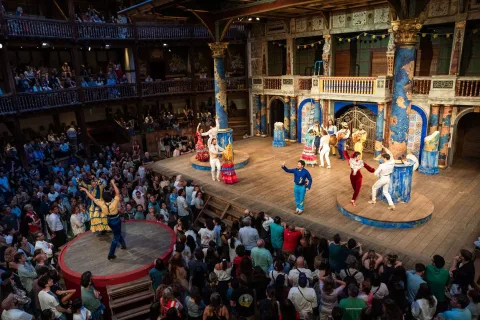 A wide shot of the Globe stage with audience surrounding.