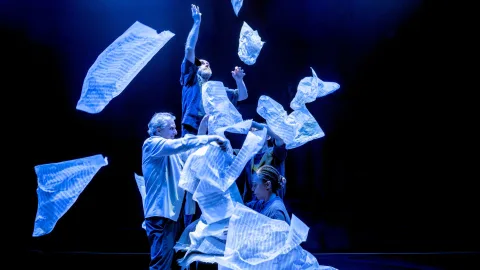 Performers throw reams of sheet music into the air