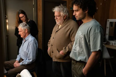 Sebastian De Souza, Simon Russell Beale and Michael Simkins getting ready backstage. They sit at dressing tables and stand in front of lit mirror. from John Gabriel Borkman
