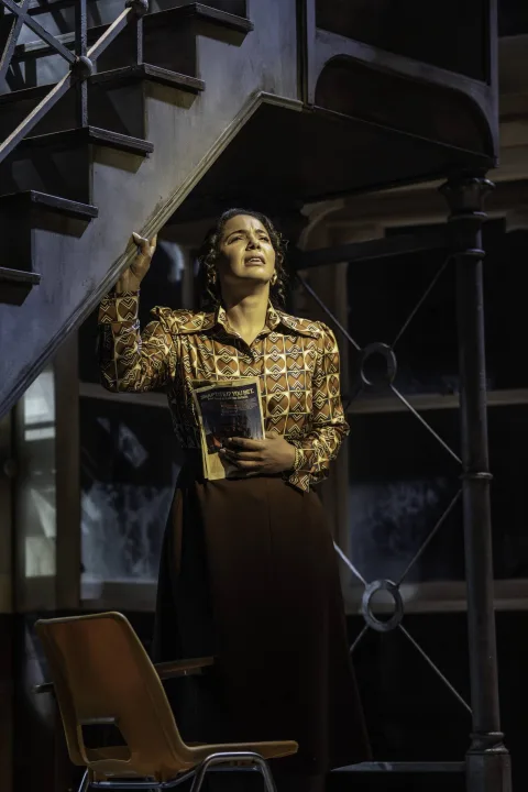 Miss Sherman (Shanay Holmes) holding a comic book and singing emotionally in a classroom. Credit: Johan Persson