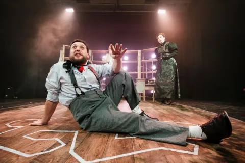 A man is reclining on the floor. You can see a forensic crime scene body outline. He is explaining something joviallly.