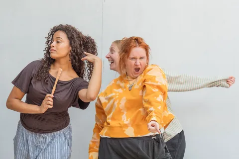 A mixed race girl, a white, ginger haired woman and a white ginger woman stand beside each other in various positions and making different facial expressions.